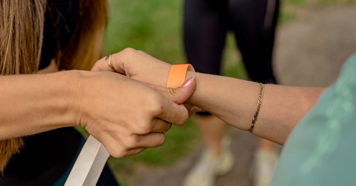 Staff applying an orange Tyvek wristband to an attendee’s wrist