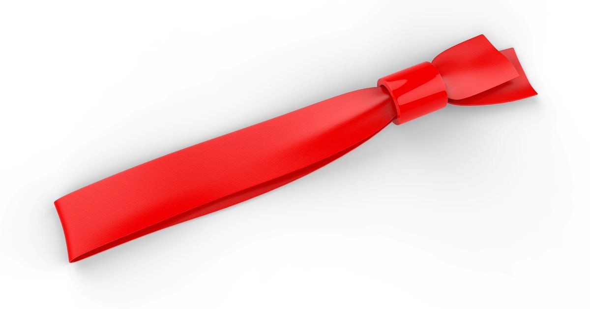 Close-up of a red fabric event wristband with a plastic locking bead