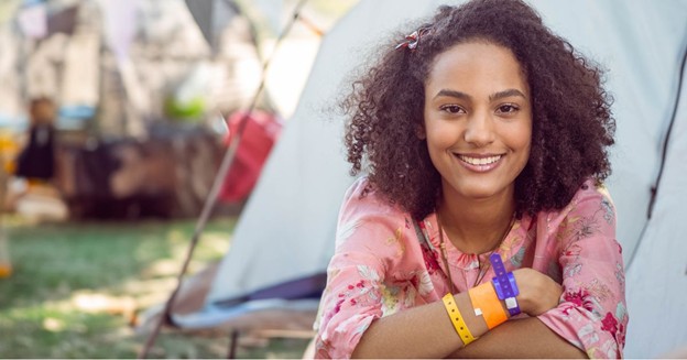 Smiling festival attendee wearing multiple colorful event wristbands
