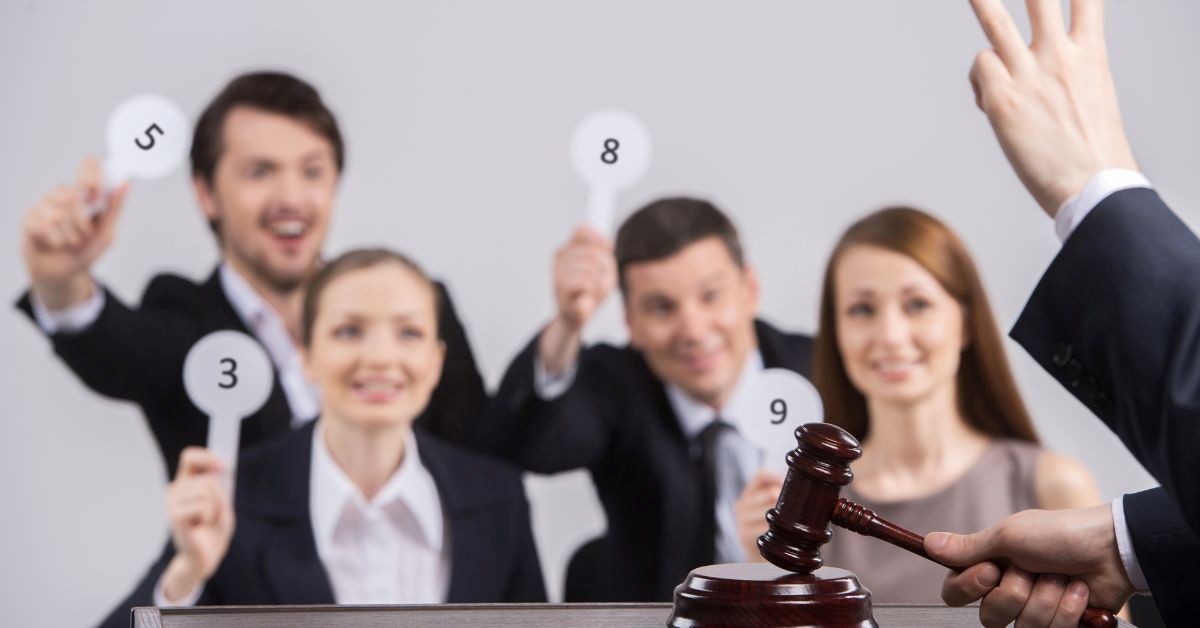 Bidders raising numbered paddles while an auctioneer gestures with a gavel