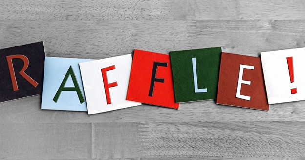 Word “RAFFLE!” spelled with colorful cutout letters on wood background
