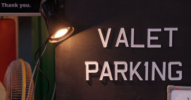 Valet parking booth sign illuminated by a small lamp
