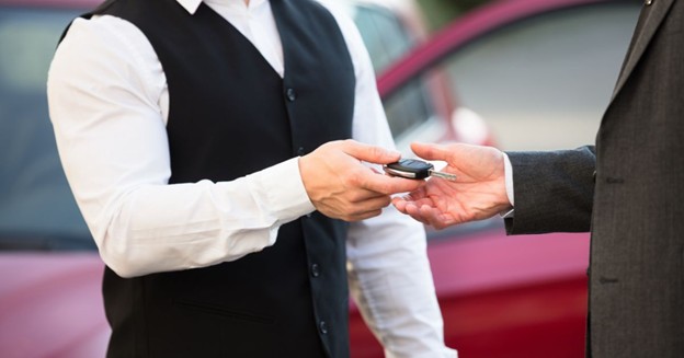 Valet attendant in vest receiving car keys from a guest