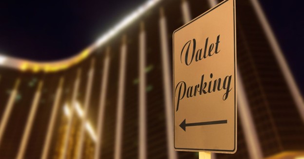Valet parking directional sign at night in front of a lit building