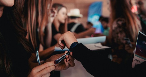 Event staff applying a wristband on a guest’s wrist at check-in