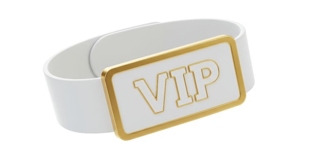 Close-up of a white wristband with a gold VIP badge