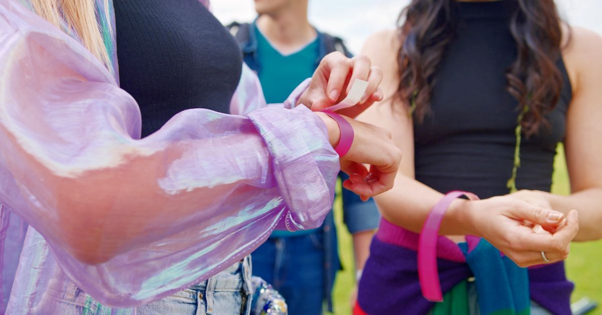 Staff applying a purple wristband to a guest’s wrist during outdoor check-in