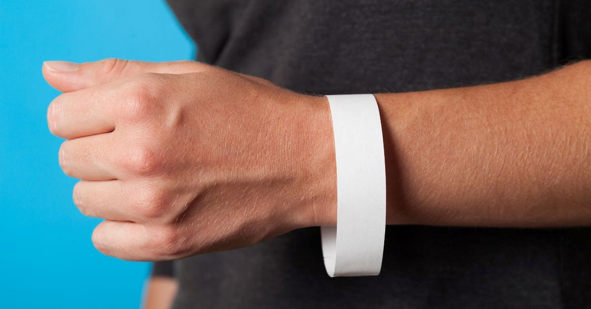 Close-up of a white event wristband on a person’s wrist
