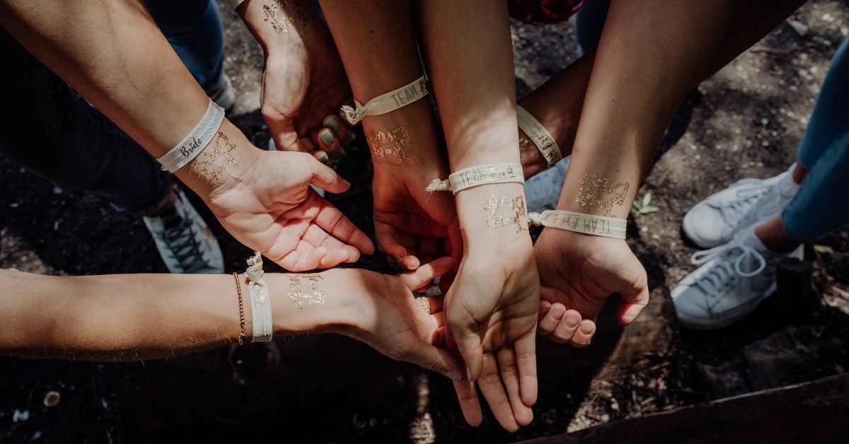 Group of attendees showing cloth wristbands and matching gold temporary tattoos