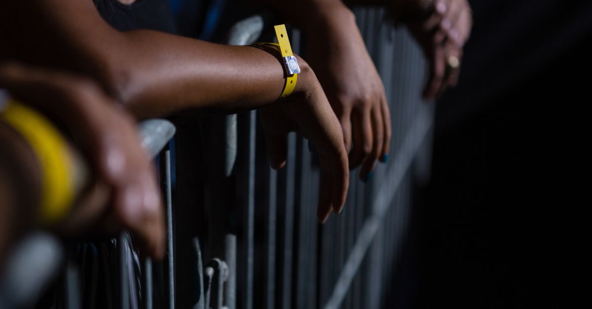 Attendees leaning on a barricade wearing yellow wristbands during a night event